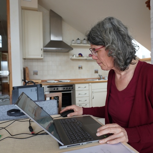 Sylvia am Laptop im Hintergrund Küche