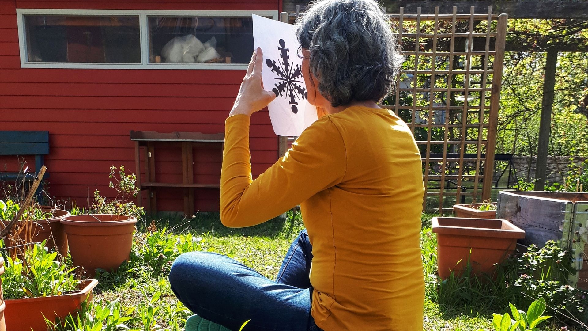 Sylvia sitzt im Garten mit dem tibetischen Rad in der Hand