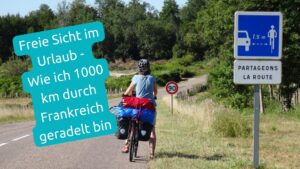 Sylvia mit Fahrrad von hinten. rote, bleue und schwarze Ortlieb Packtaschen, Verkehrsschild 90 und Verkehrsschild halte Abstand zu Radfahrern