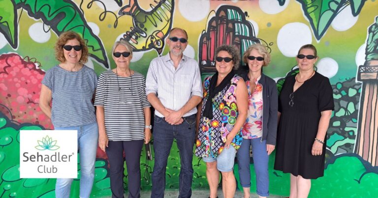 mehrere Clubmitglieder stehen vor einer Grafittiwand mit Darmstädter Sehenswürdigkeiten und lachen in die Kamera