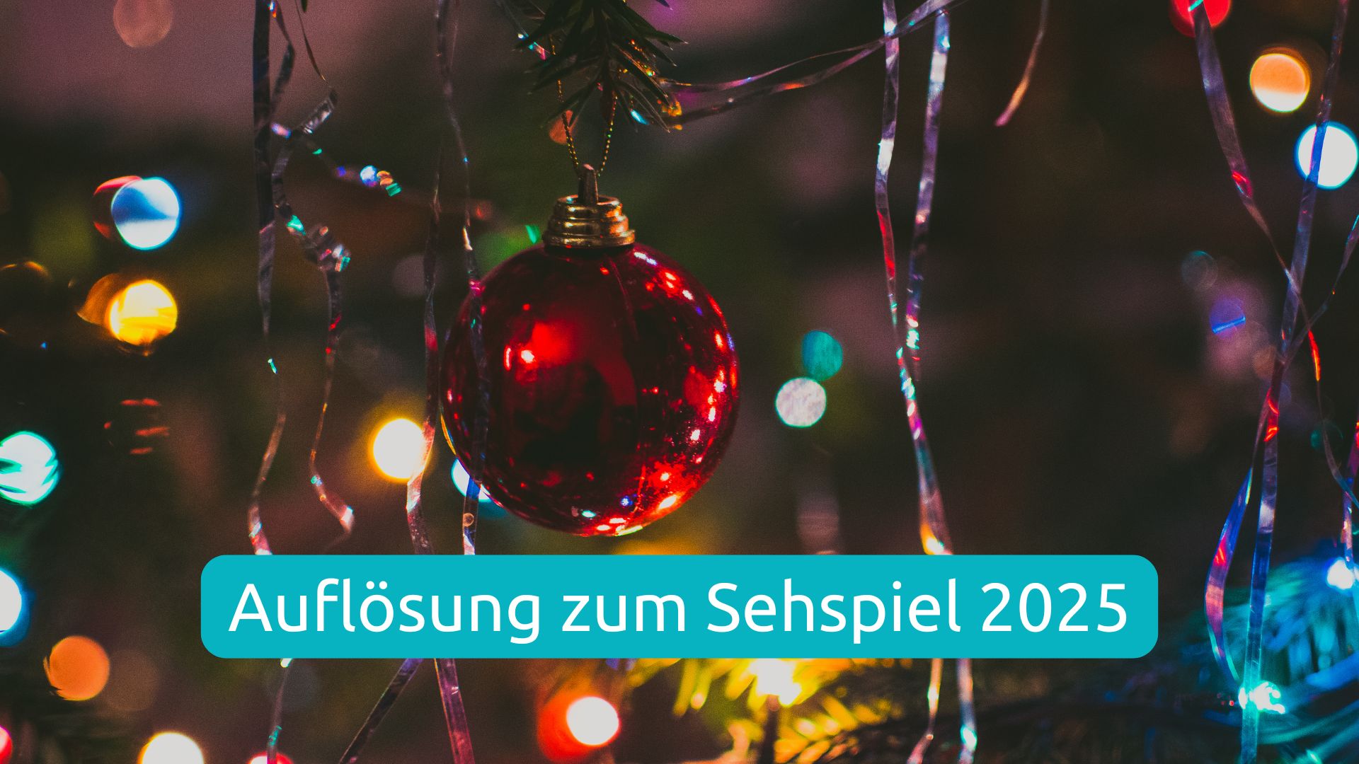 Auflösung zum Weihnachts-Sehspiel 2025, eine rote Kugel hängt an einem Tannenzweig, es sind viele bunte Lichtpunkte und Lametta zu sehen.
